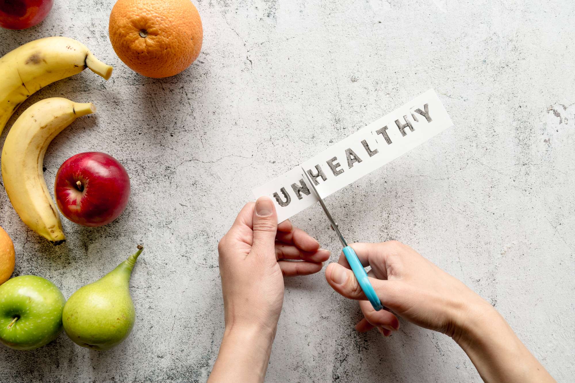 human-hand-cutting-unhealthy-word-with-scissor-near-healthy-fruits.jpg