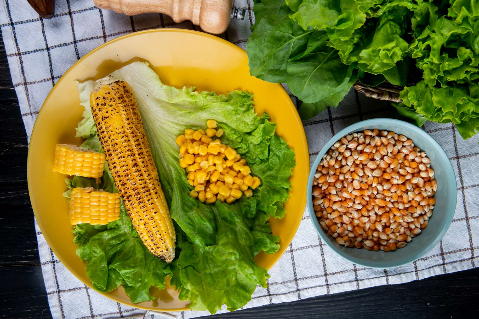 close-up-view-whole-cut-corns-corn-seeds-with-lettuce-plate-spinach-plaid-cloth.jpg