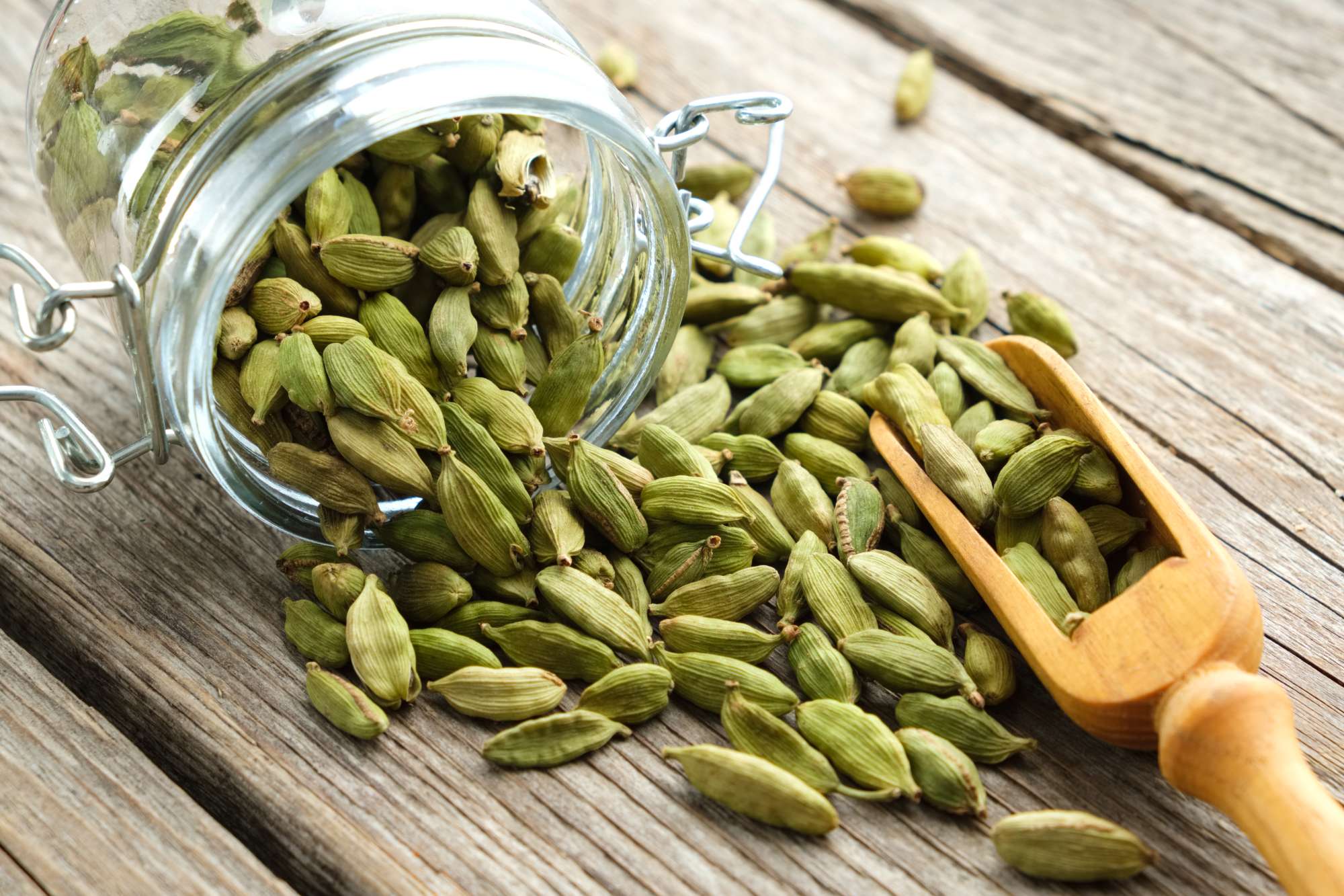 green-aromatic-cardamom-pods-jar-whole-cardamom-pods-wooden-scoop-table.jpg