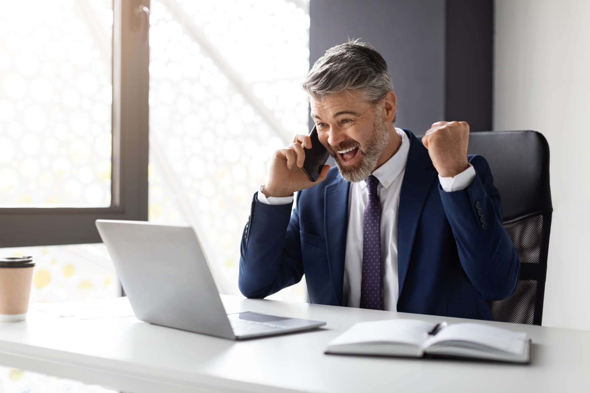 joyful-middle-aged-businessman-with-cellphone-laptop-celebrating-success-office.jpg