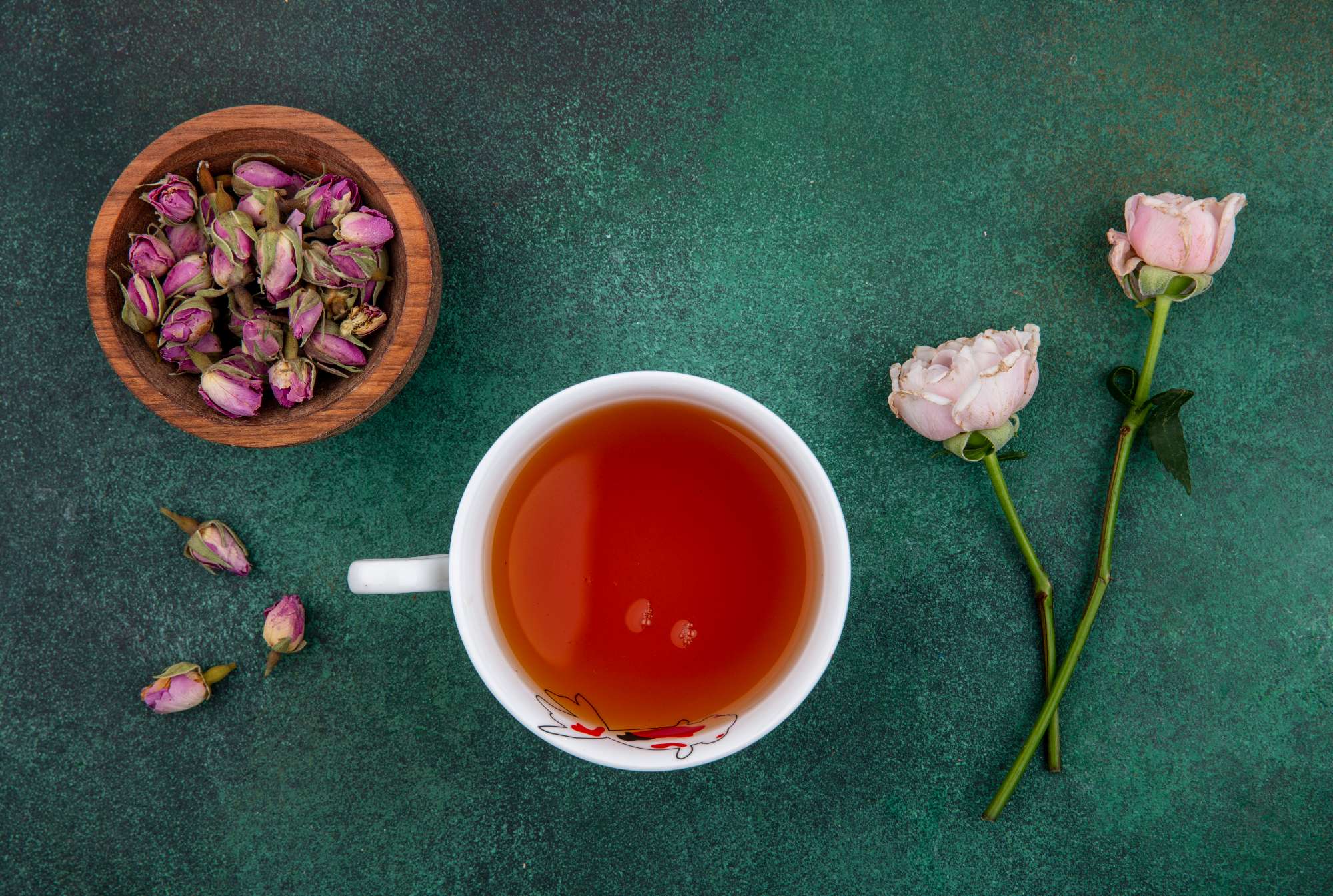 top-view-cup-tea-with-light-pink-roses-dried-rose-buds-bowl-green-surface.jpg