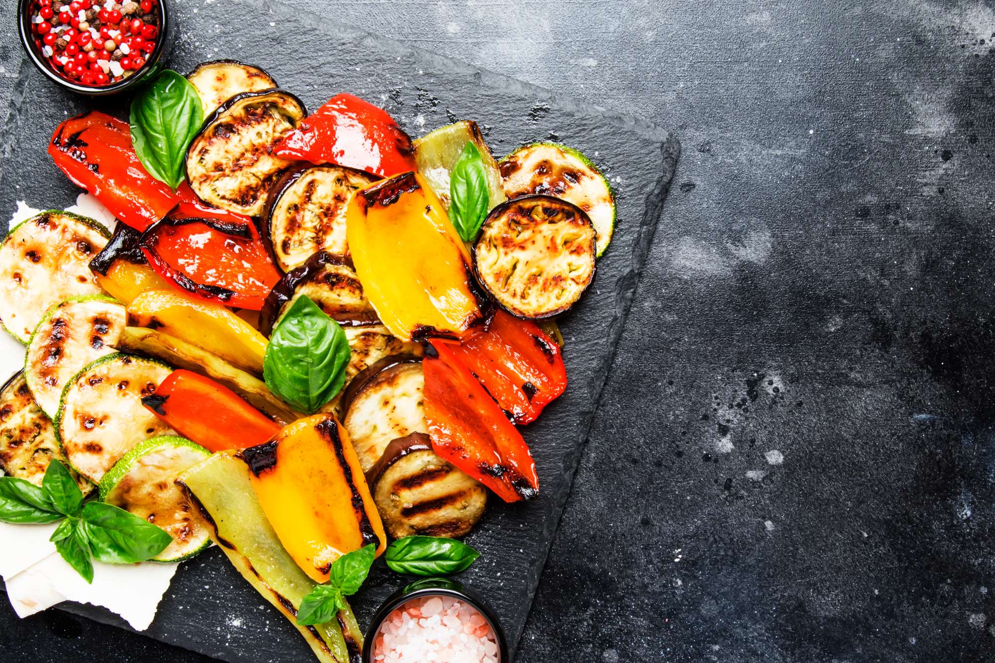 grilled-multicolored-vegetables-aubergines-zucchini-pepper-with-green-basil-serving-stone-board-gray-background-top-view.jpg