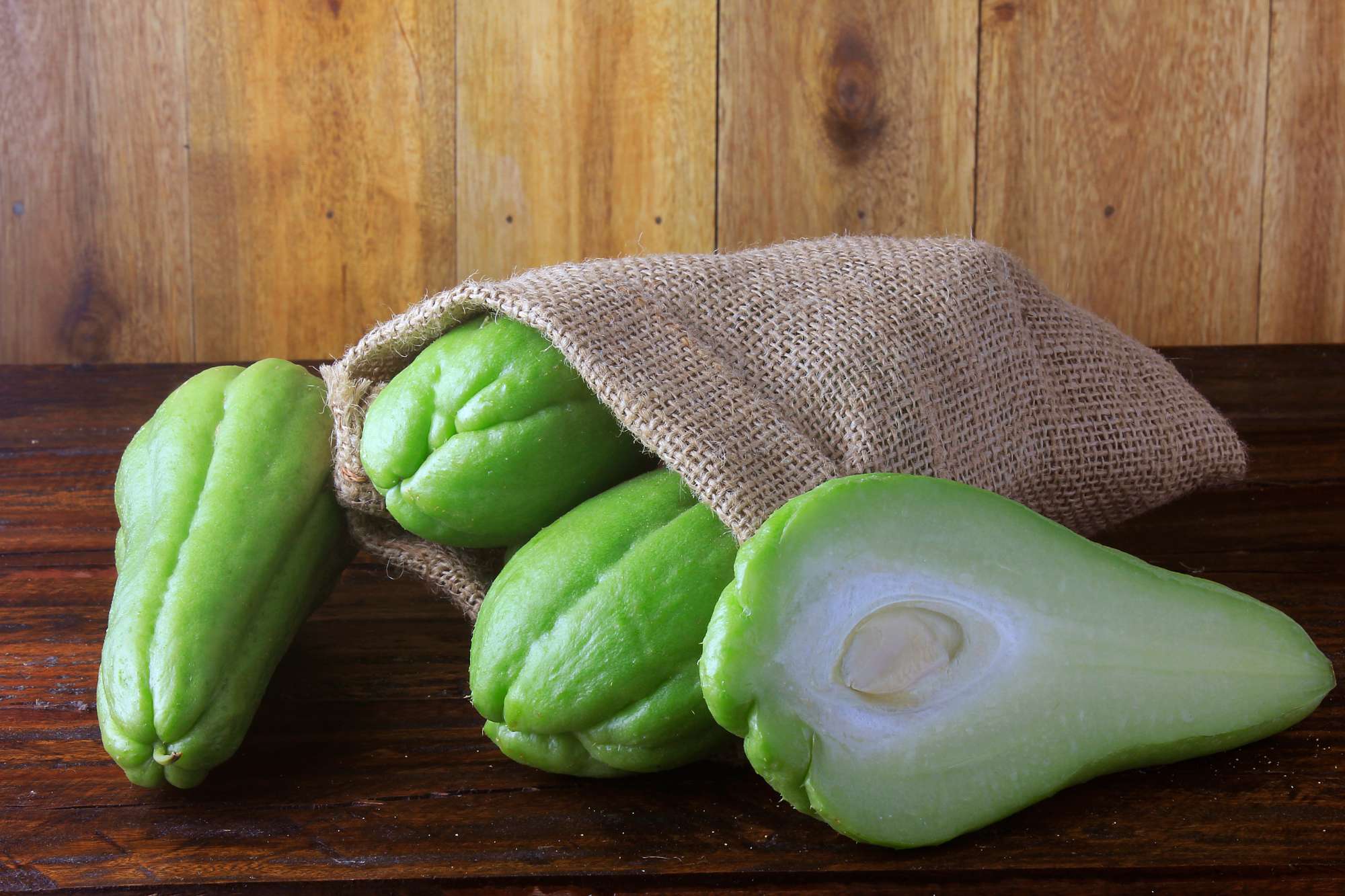 raw-fresh-organic-chayote-whole-sliced-rustic-bag-wooden-table.jpg