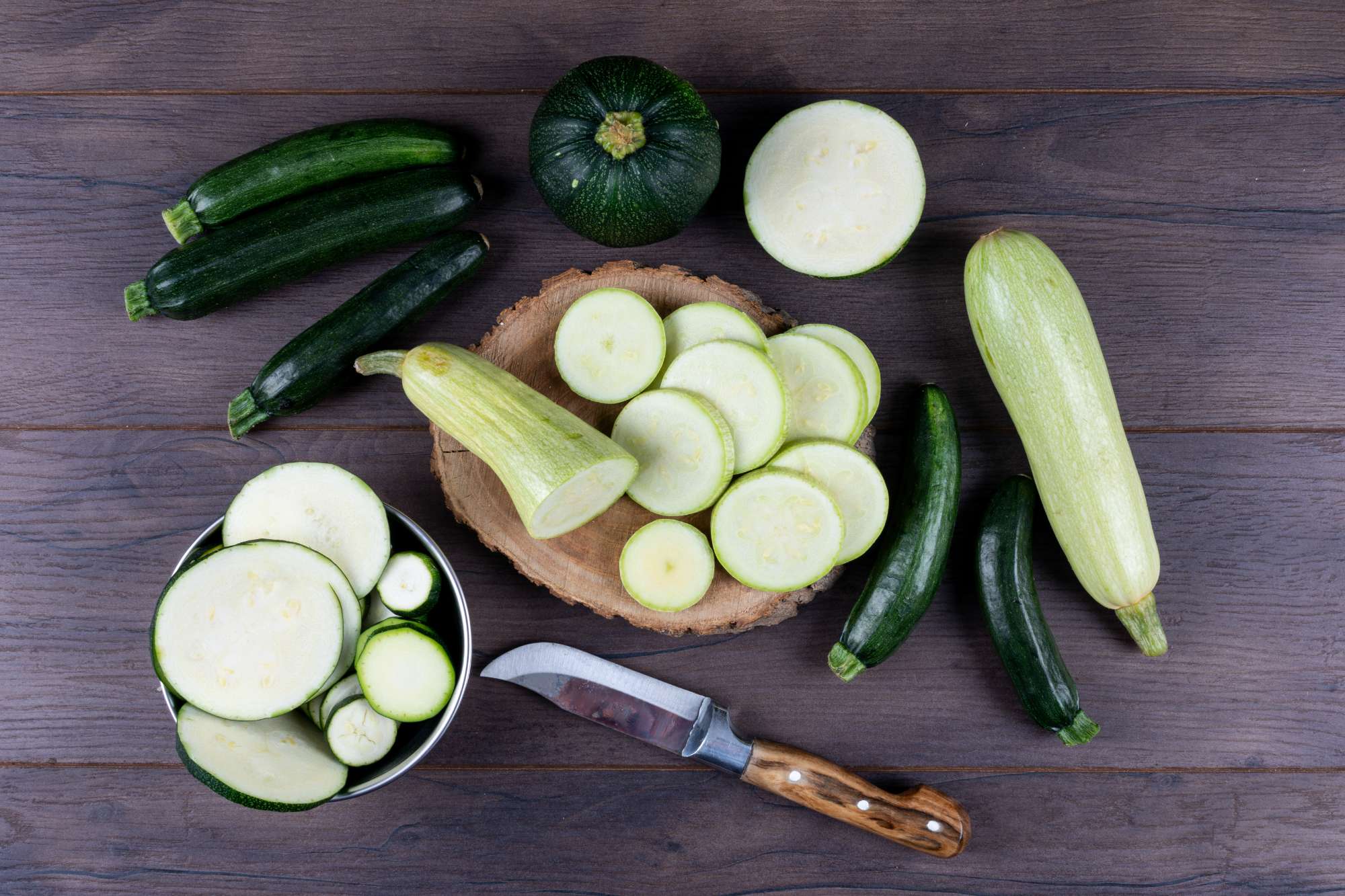 set-knife-other-zucchinis-bowl-around-sliced-zucchinis-dark-wooden-table-flat-lay.jpg