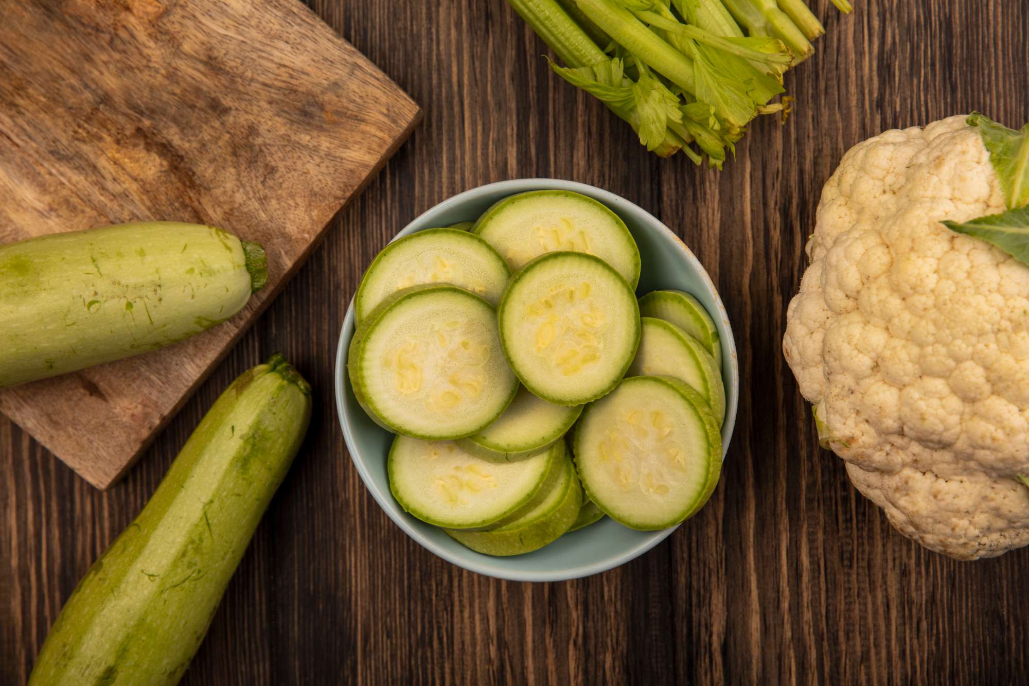 top-view-organic-chopped-zucchinis-bowl-with-celery-zucchinis-cauliflower-isolated-wooden-surface.jpg